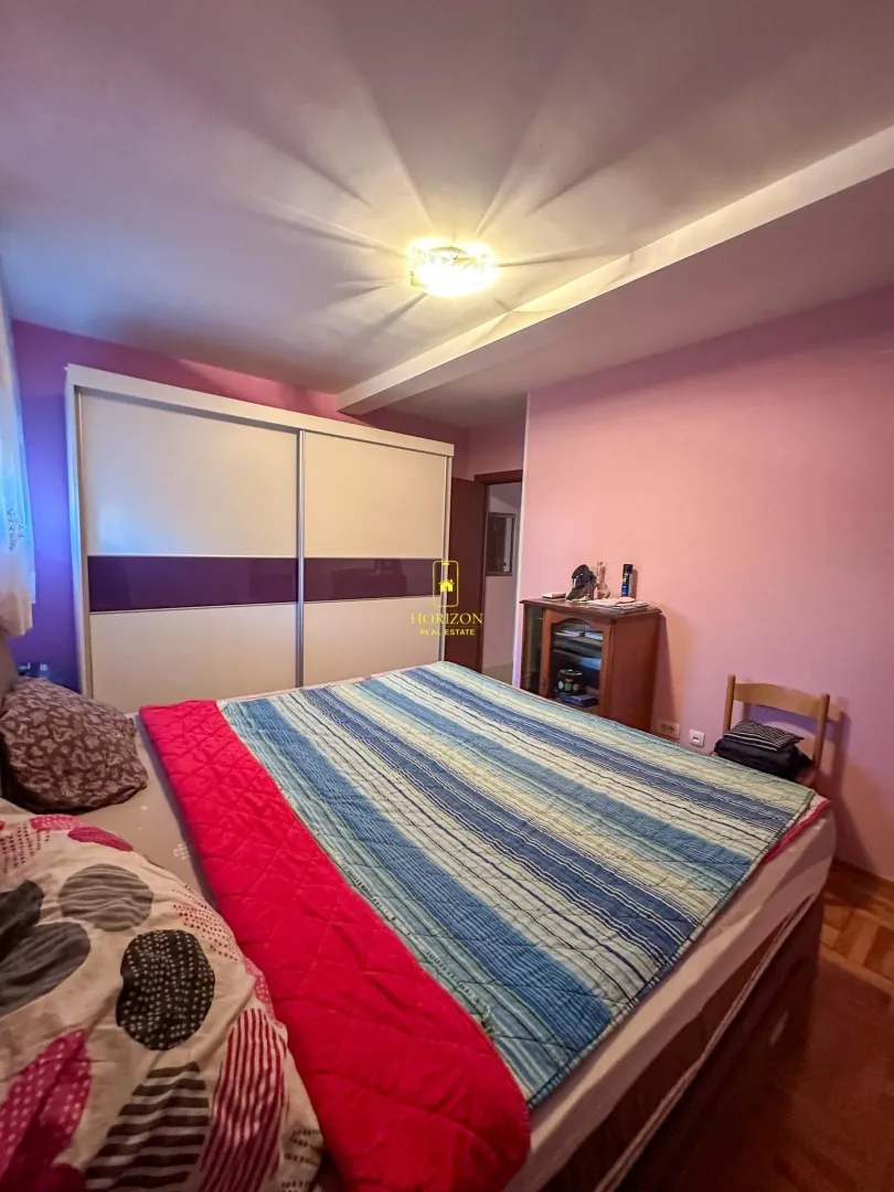 Spavaća soba sa bračnim krevetom, garderoberom i roze zidovima.