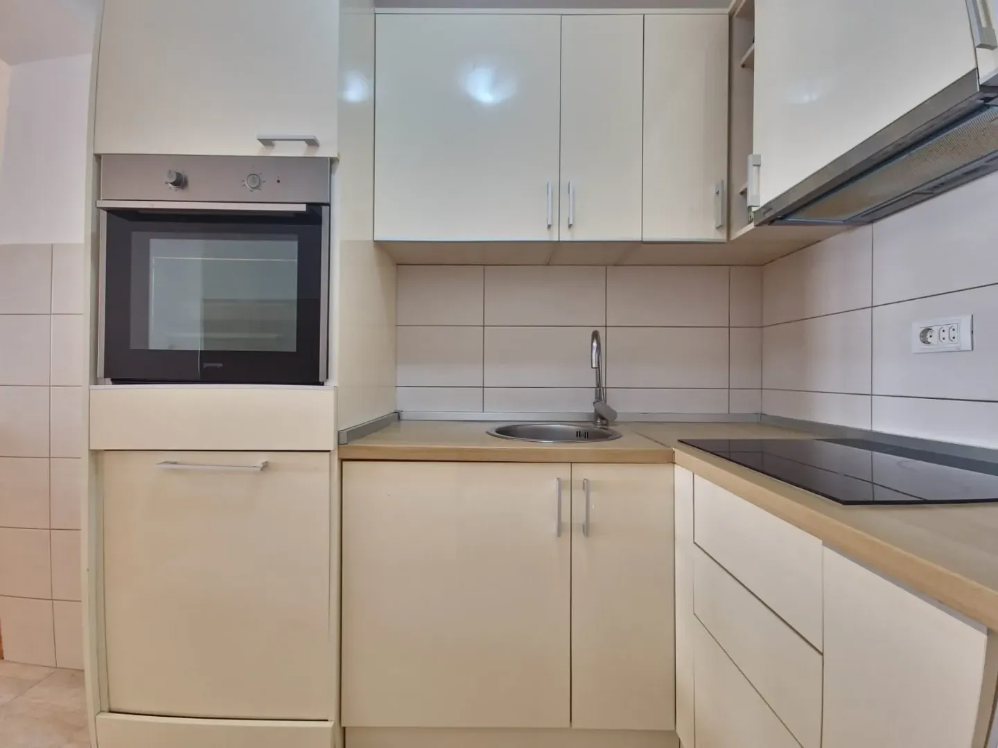 Kitchen with light cabinets, built-in oven, and a sink.