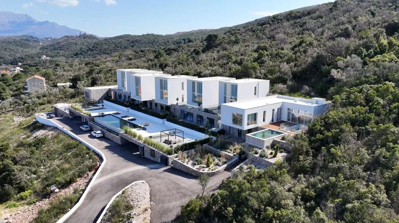 Pogled iz vazduha na kompleks modernih vila sa bazenima i uređenim okruženjem.