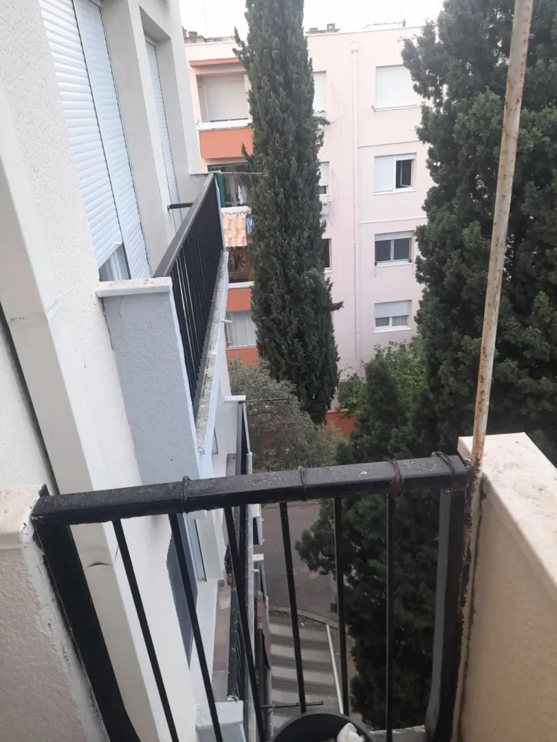 Pogled sa balkona na susjedne zgrade i drveće.