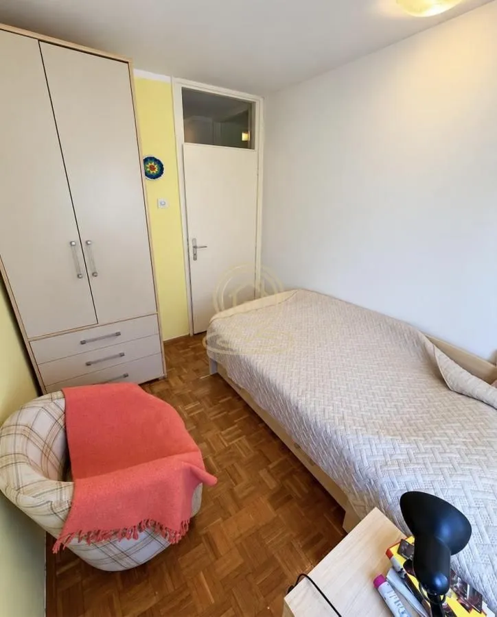 Furnished bedroom with a bed, wardrobe, and armchair.