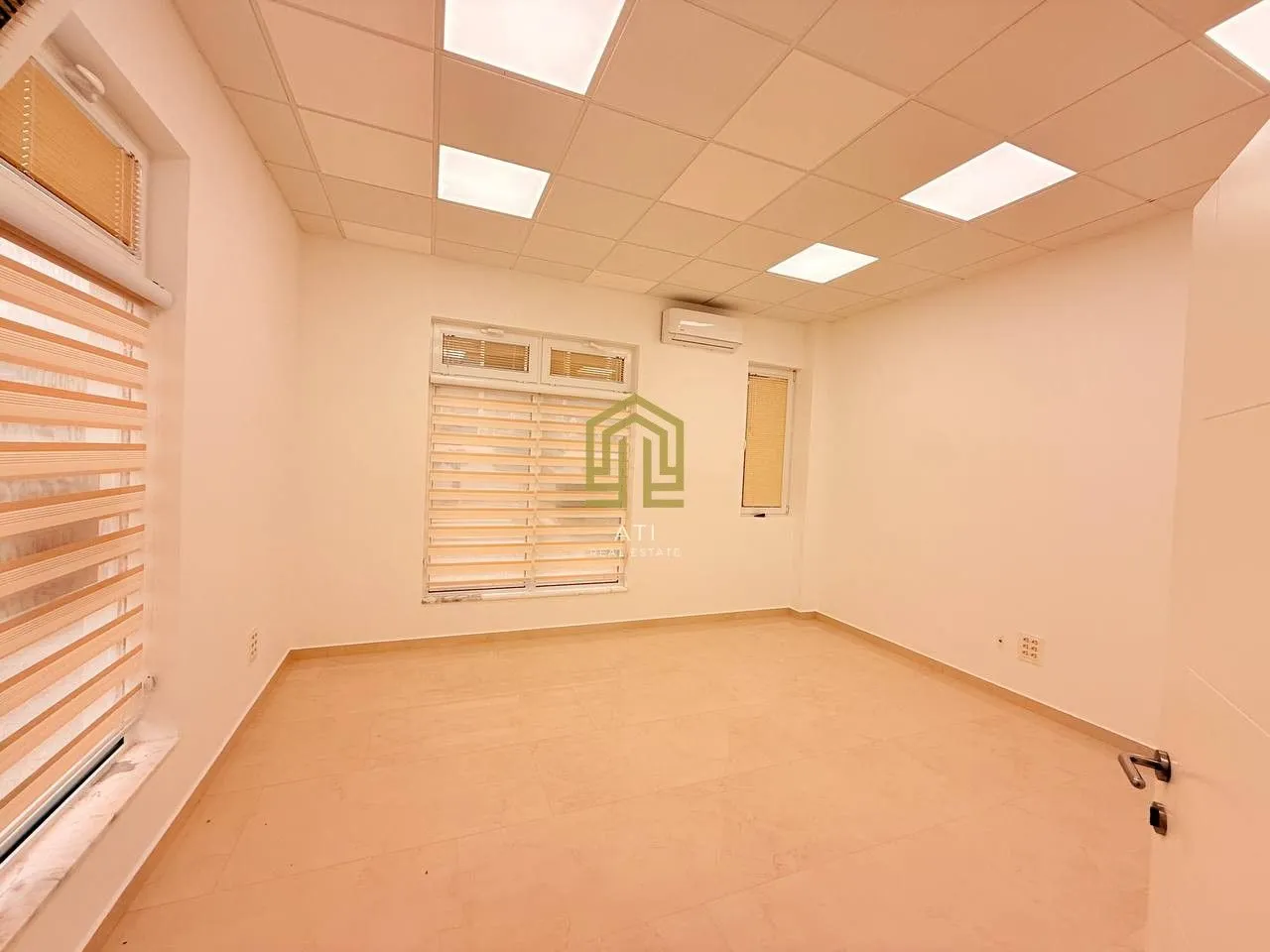 Empty office space with a dropped ceiling and lighting.