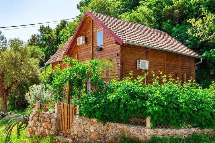 Exterior view of a wooden house with a landscaped yard and greenery.