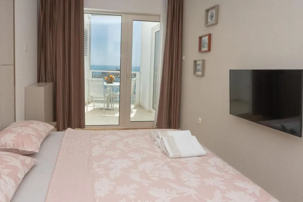 Furnished bedroom with a double bed, TV, and access to a terrace with a sea view.