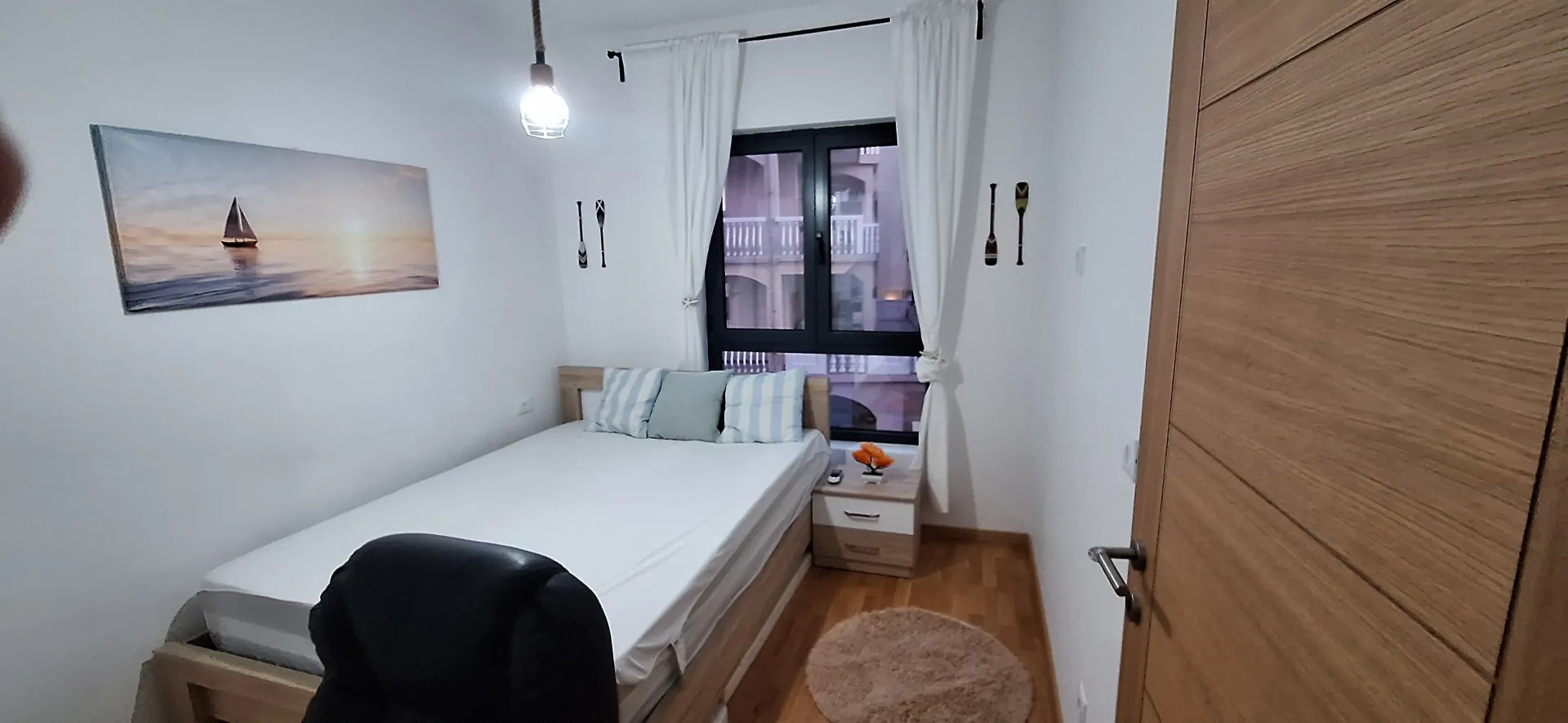 Small bedroom with a double bed, nightstand, and a window.