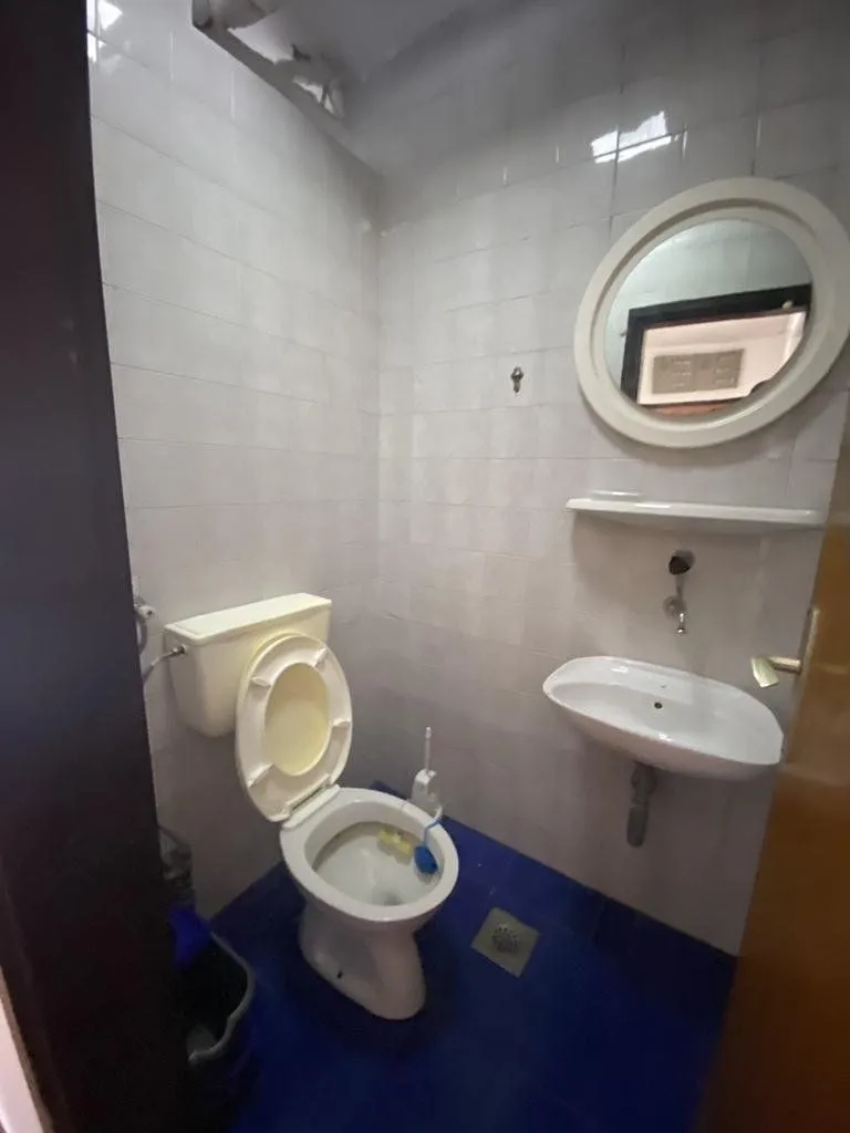 Smaller bathroom with a toilet, washbasin, and a round mirror.
