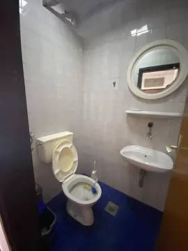 Smaller bathroom with a toilet, washbasin, and a round mirror. - image 8