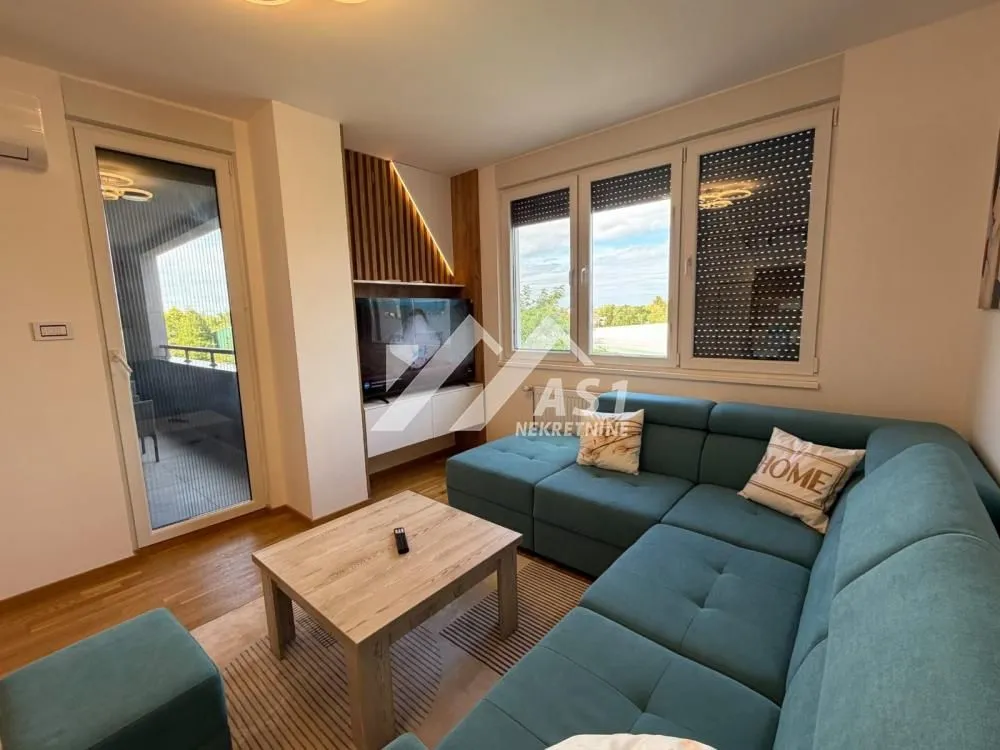 Living room with a large sectional sofa, coffee table, and access to the terrace.