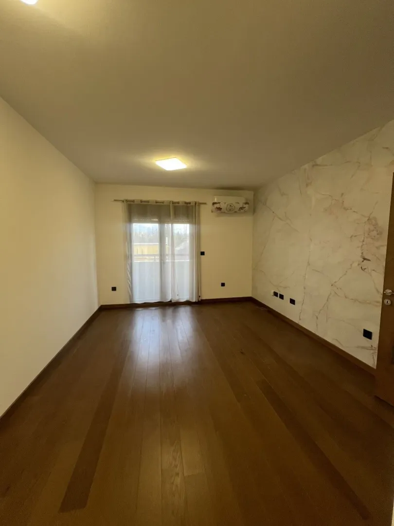 An empty room with wooden floors and a decorative accent wall.
