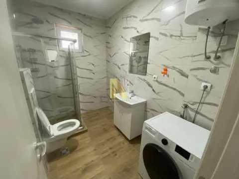 Bathroom equipped with a walk-in shower, washbasin, toilet, and washing machine. - image 15