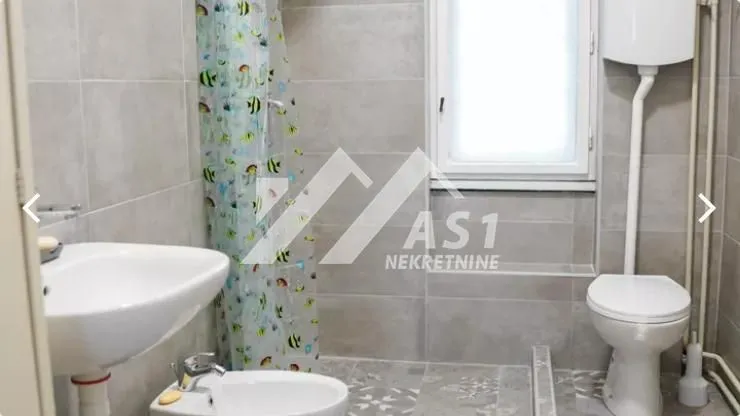 Kupatilo opremljeno sanitarijama i tuš kabinom sa zavesom.