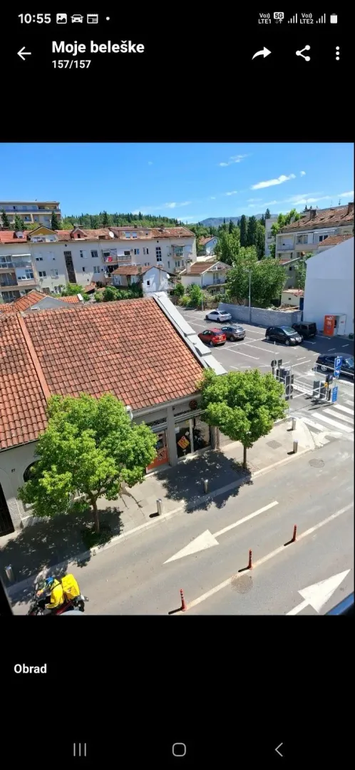 Pogled sa prozora na ulicu, parking i okolne zgrade.