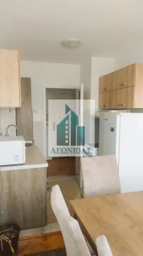 Small kitchen with wooden cabinetry and a dining table in the foreground. - image 7