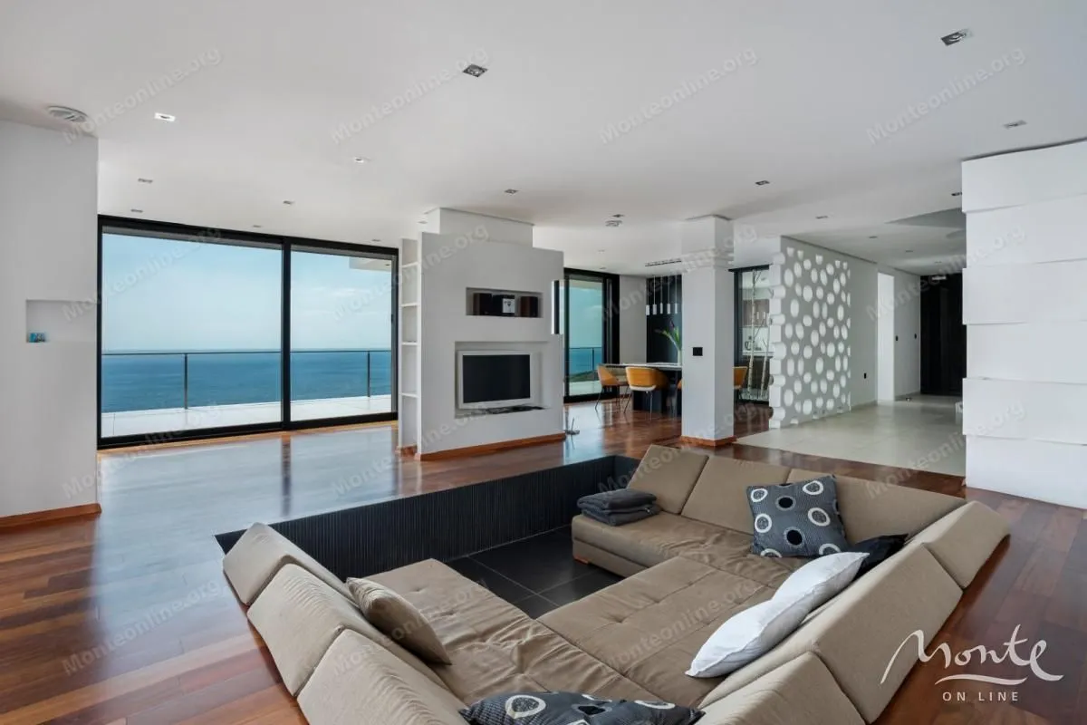 Spacious living room with a comfortable sectional sofa, fireplace, and sea view.