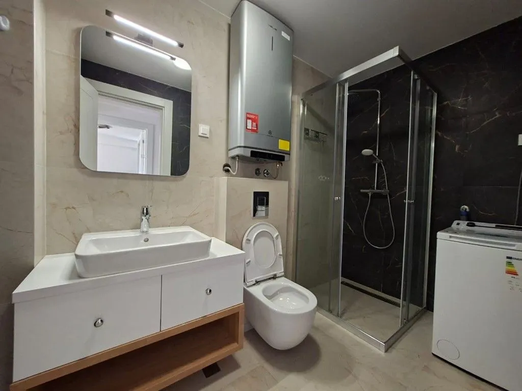 Moderne kupatilo sa umivaonikom, WC šoljom, tuš kabinom i bojlerom.