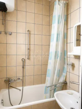 Kupatilo sa kadom, tušem, umivaonikom i pločicama u bež tonovima. - image 7