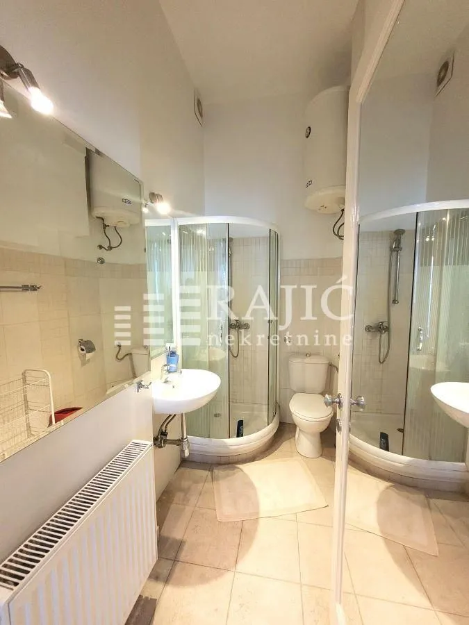 Smaller bathroom with a shower cabin, washbasin, and toilet.