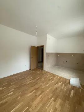 Prazna soba sa drvenim podom i pripremljenim dijelom za kuhinju. - image 2