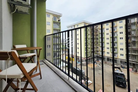 Small balcony with a wooden table and chairs and a view of surrounding buildings under construction. - image 2