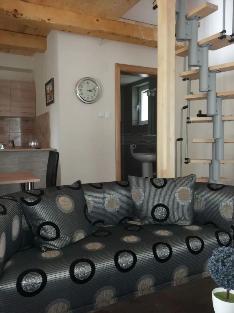 Dnevna soba sa garniturom i drvenim stepeništem.