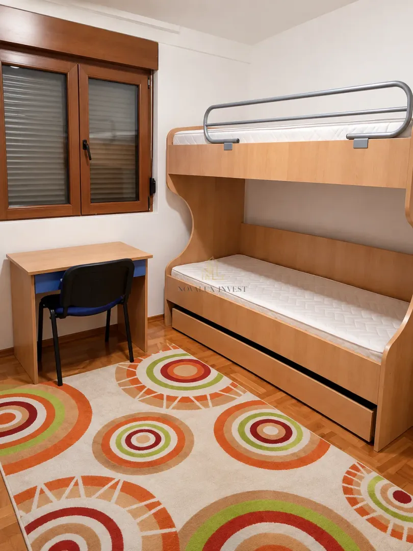 Children's bedroom with a bunk bed, desk, and a window.