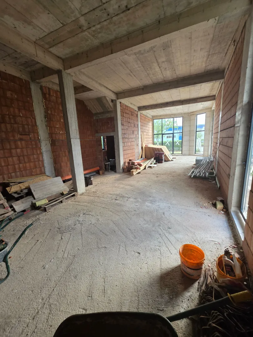 View of an unfinished room under construction with concrete pillars and brick walls.