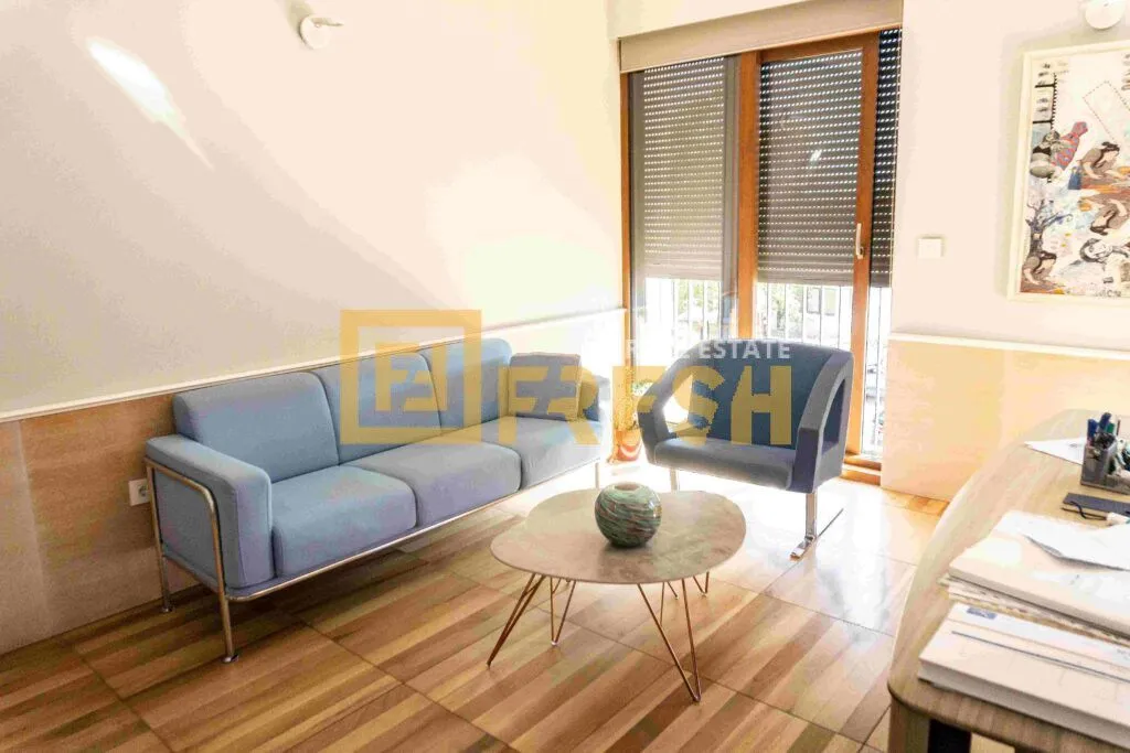 Living room with a blue sofa, armchair, coffee table, and access to the terrace.