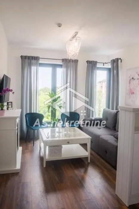 Comfortable living room with a sofa, coffee table and large windows.