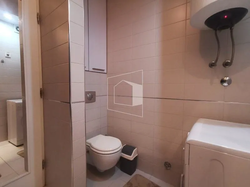 Small bathroom with a toilet, water heater, and tiled walls.