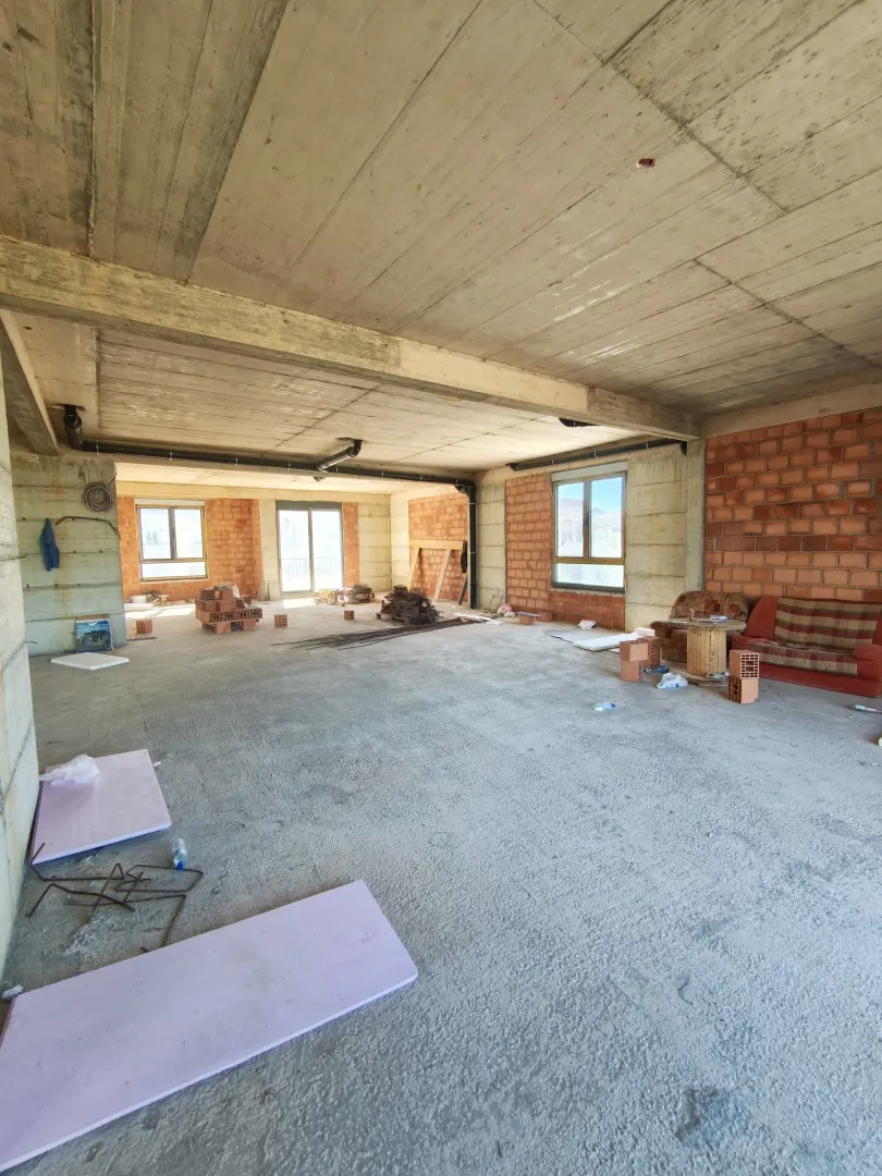 View of an unfinished space under construction with concrete floors and brick walls.