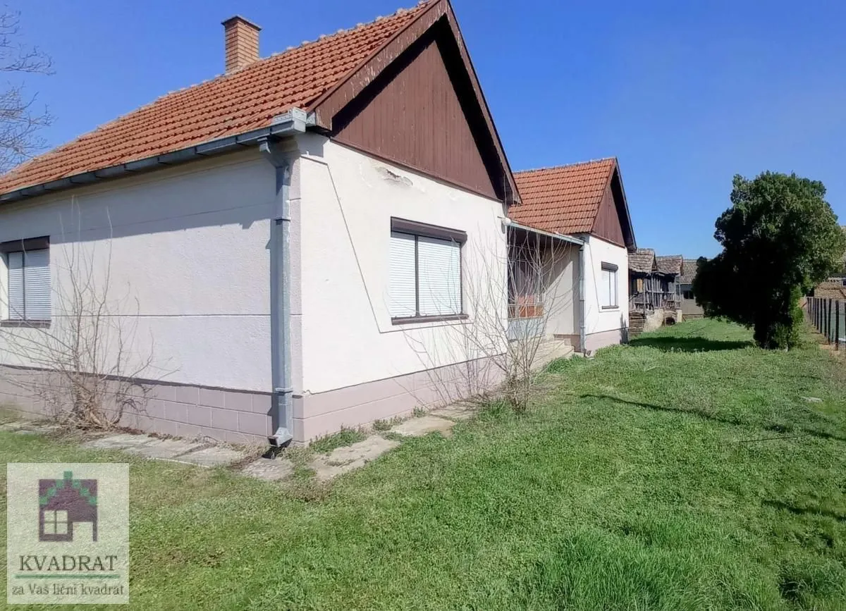 Pogled na spoljašnjost prizemne kuće sa travnatim dvorištem.