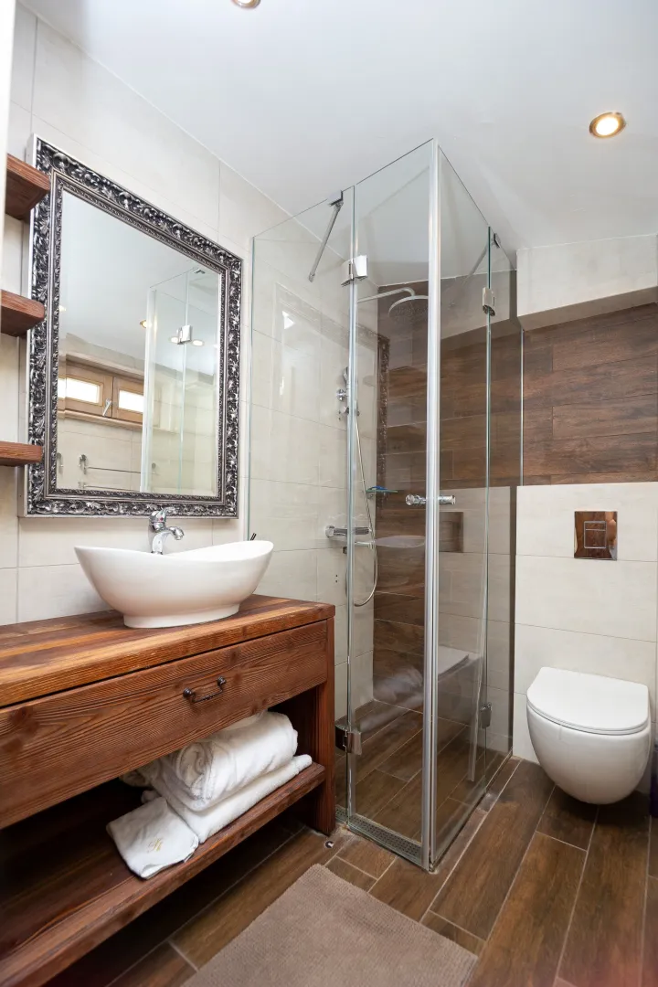 Modern bathroom with wooden elements, washbasin, shower cabin, and toilet.