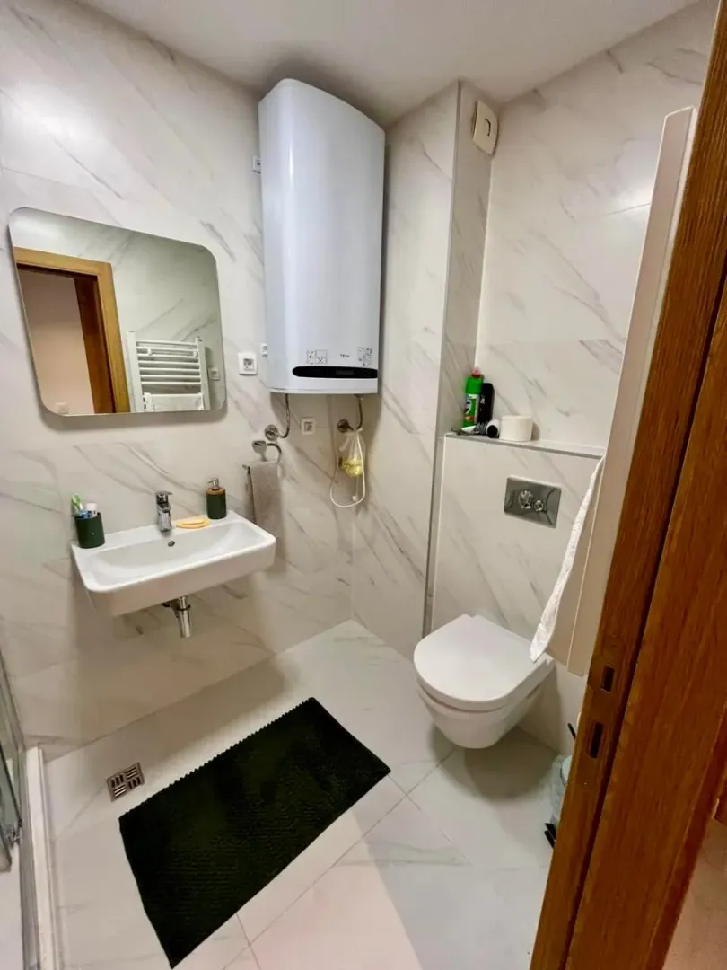 Small bathroom with a washbasin, toilet, and water heater.