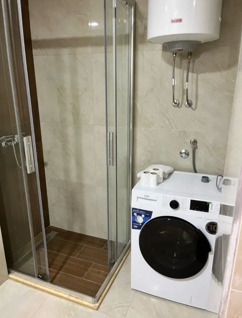 Small bathroom with a shower cabin, washing machine, and water heater.