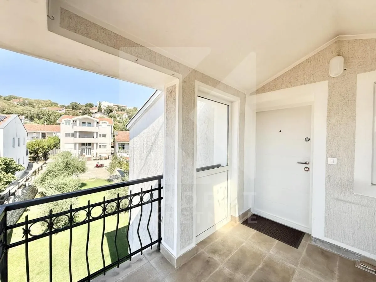 Covered balcony with an entrance door and a view of the surroundings.