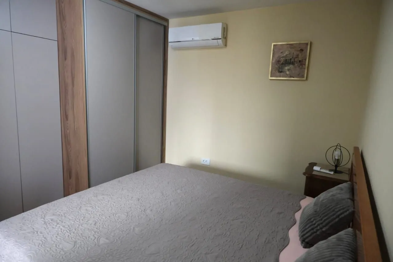 A simply furnished bedroom with a built-in wardrobe and air conditioning.
