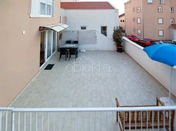 Velika popločana terasa sa garniturom za sjedenje i stolom.