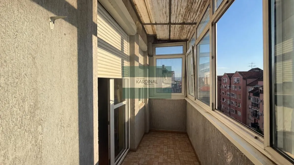 Zastakljeni balkon sa pogledom na susedne zgrade.