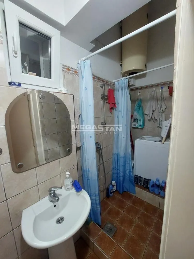Smaller bathroom with a shower cabin, washbasin, and water heater.