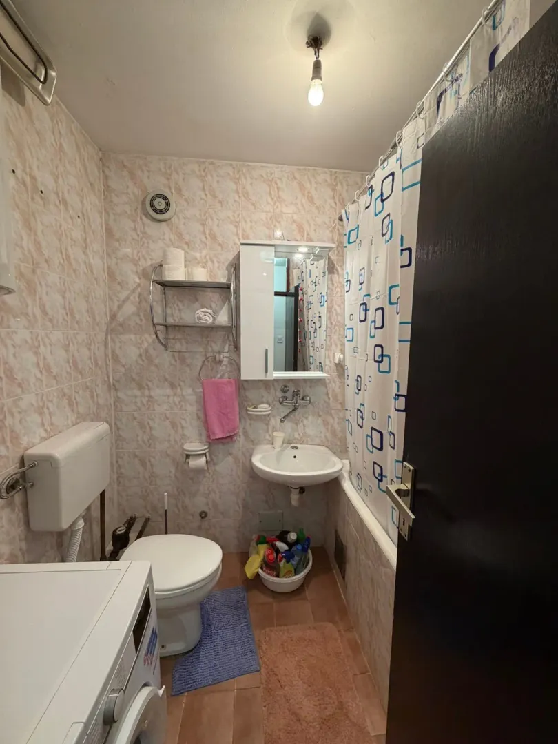 Small bathroom with bathtub, washbasin, toilet, and washing machine.