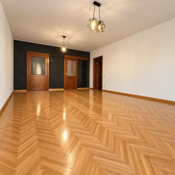 Empty spacious living room with wooden parquet flooring and hanging chandeliers. - image 2