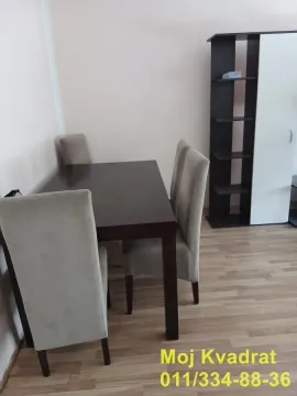 Dining table with chairs and a shelving unit in the corner. - image 5