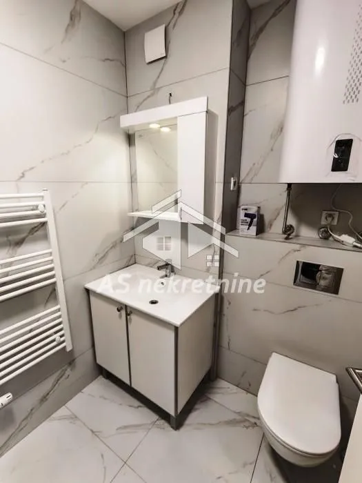 Modern bathroom equipped with a vanity, toilet, and marble-look tiles.