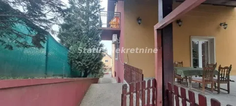 Pogled na spoljni deo kuće sa dvorištem, terasom i drvenom ogradom. - image 5