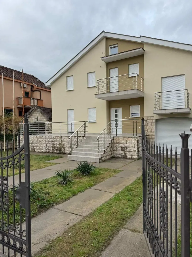 Exterior view of a two-story house with a yard and a gate.