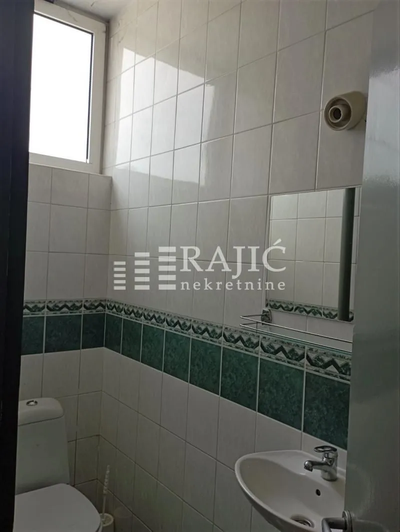 Small bathroom with white and green tiles.