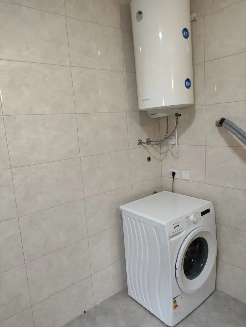 Part of a bathroom with a washing machine and a wall-mounted water heater.