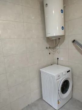 Part of a bathroom with a washing machine and a wall-mounted water heater. - image 11