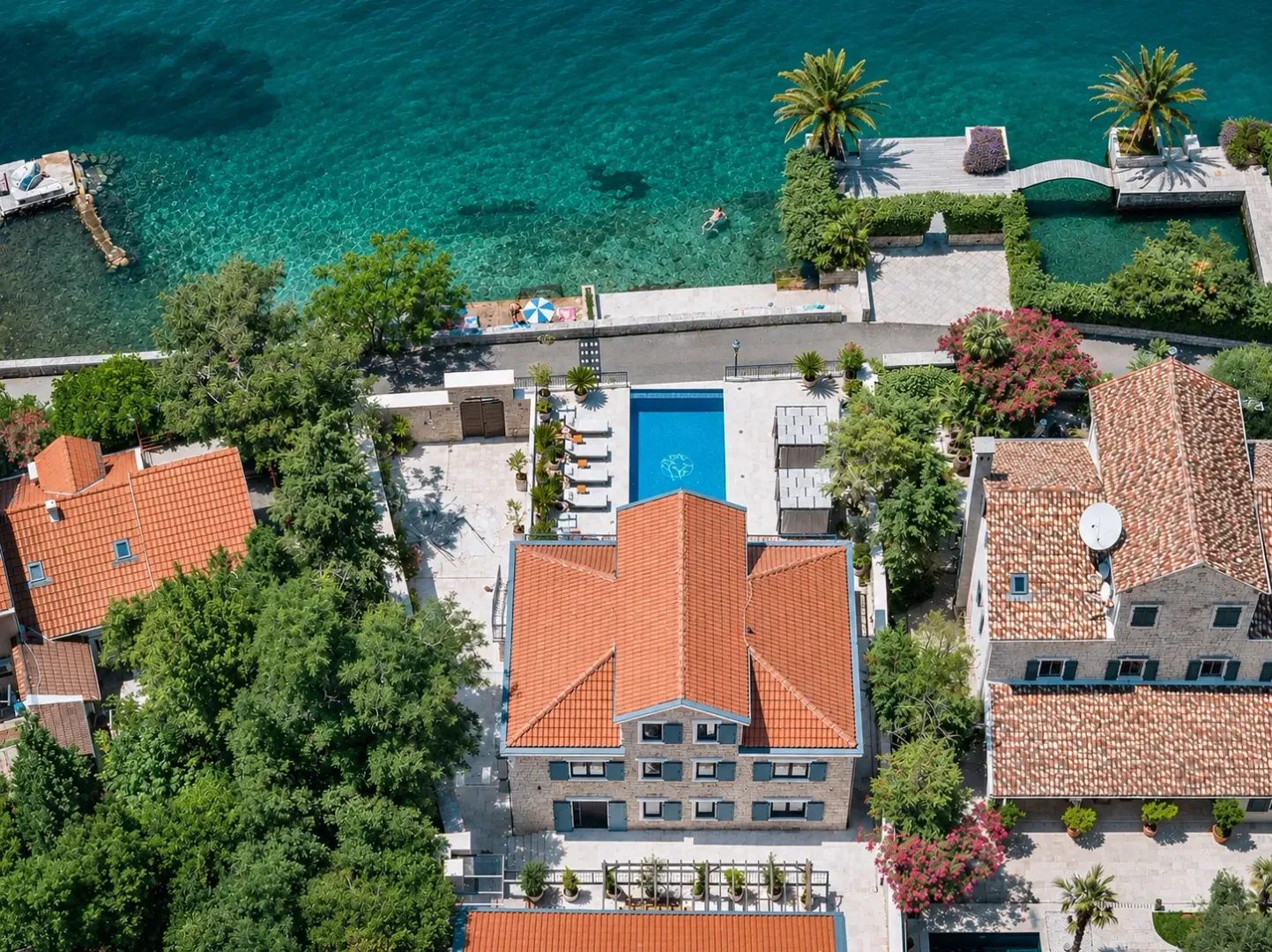 Aerial view of a villa with a swimming pool and courtyard by the sea.