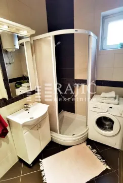 Compactly equipped bathroom with a shower cabin, washbasin, and washing machine. - image 11